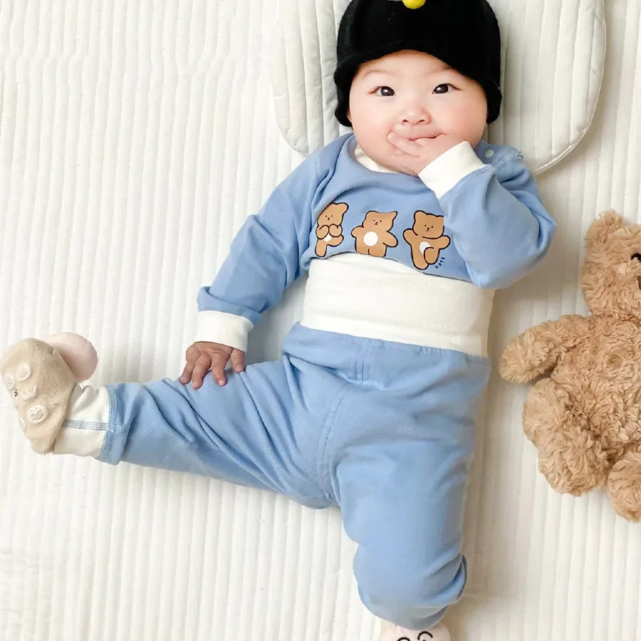 Baby wearing Baby 2PCS Pajama Set Cotton Long Sleeve Outfit for Autumn Winter Wear in blue with bear design lying on bed