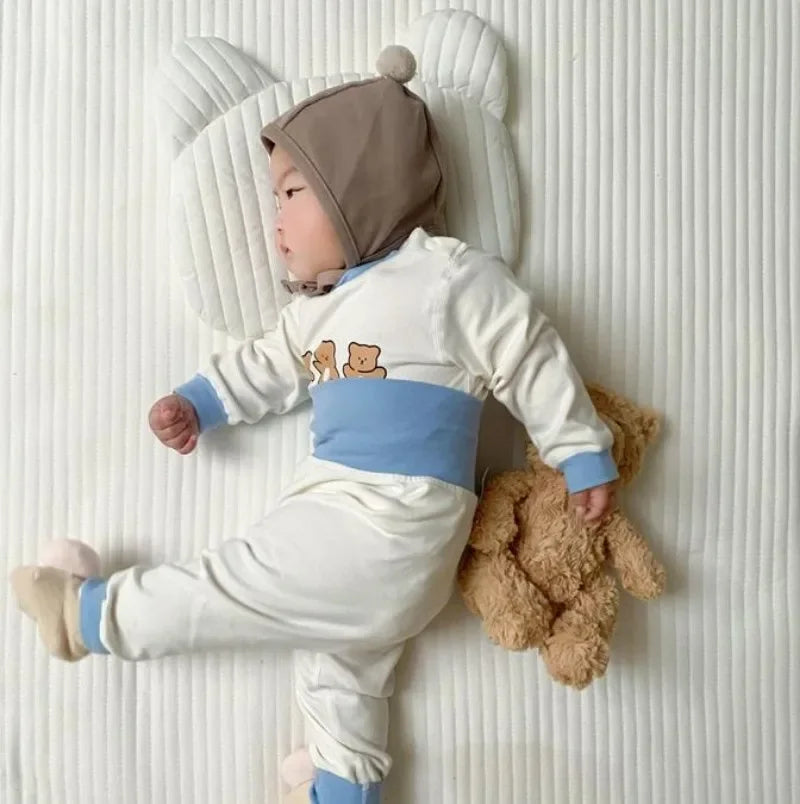 Baby wearing Baby 2PCS Pajama Set Cotton Long Sleeve Outfit for Autumn Winter Wear lying next to teddy bear on white quilted blanket