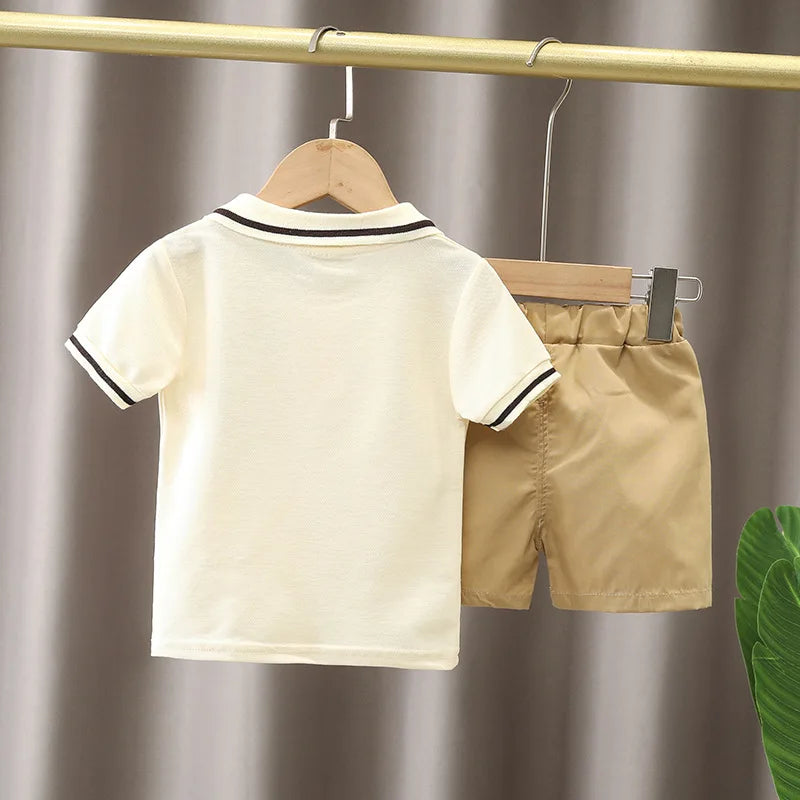 Yamza Tots' Closet baby boy clothes set with cream polo shirt and khaki shorts hanging on wooden hangers