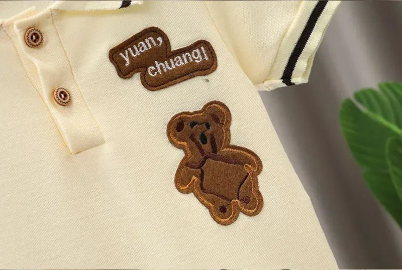 Cream baby boy clothes set with brown teddy bear patch and embroidered text on the chest