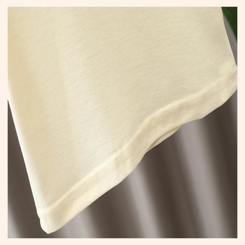Close-up of the soft cotton fabric and stitching on a light-colored baby boy t-shirt suitable for summer wear.