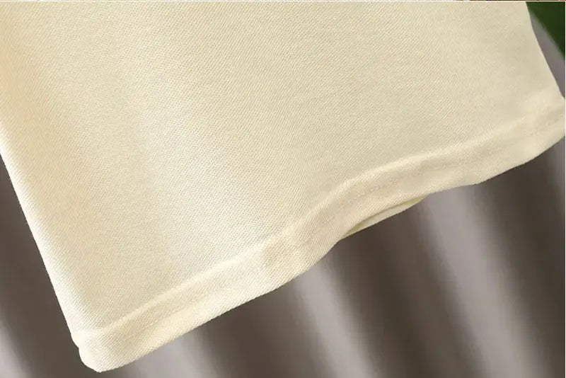 Close-up view of cream fabric detail from Yamza Tots' Closet baby boy clothes set