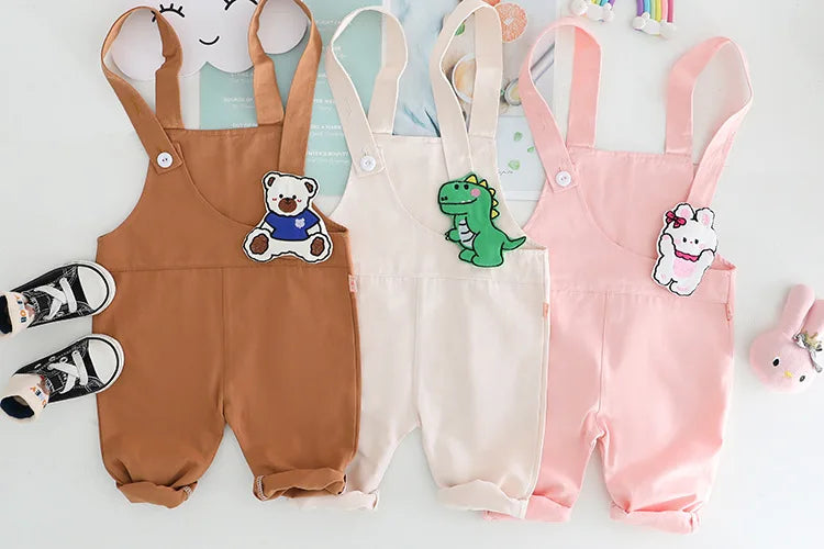 Yamza Tots Closet baby girls and boys clothing with cute brown, white, and pink overalls featuring bear, dinosaur, and bunny patches