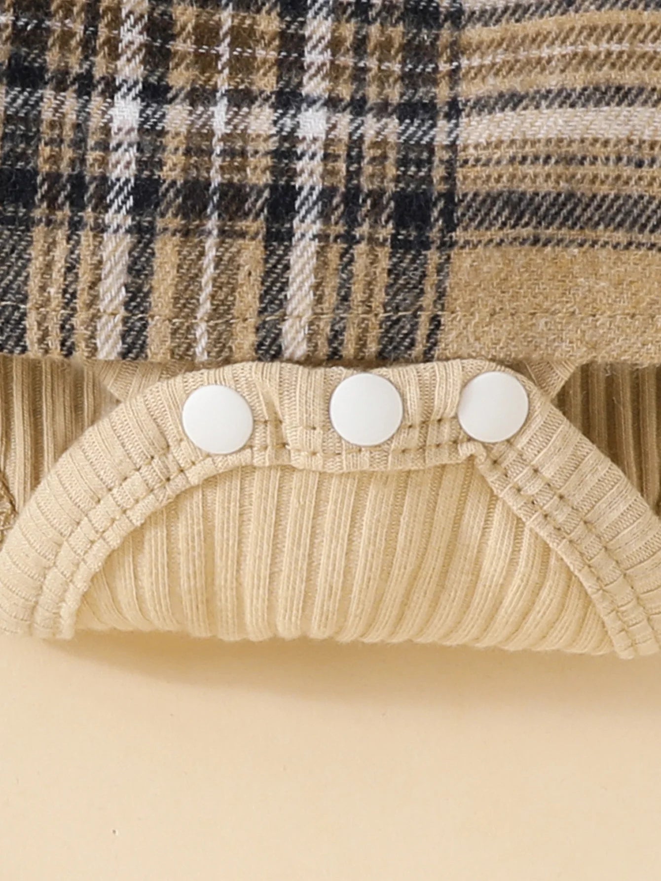 Close-up of Baby Girls Long Sleeve Plaid With Bow outfit showing cream ribbed fabric and button snaps
