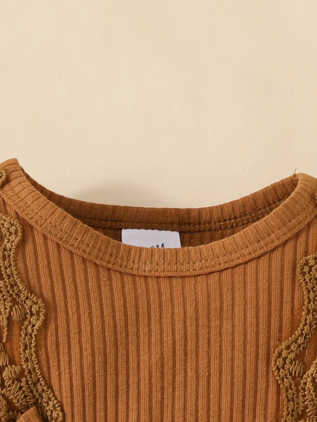 Close-up of ribbed brown knit fabric baby top with decorative trim from Yamza Tots' Closet