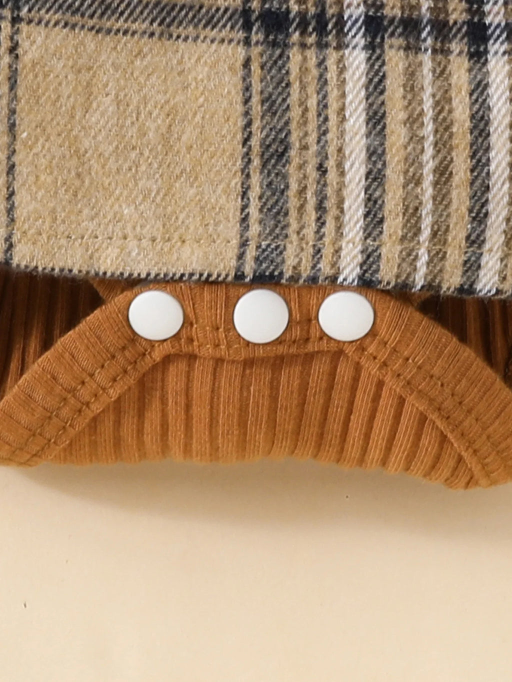Close-up of Baby Girls Long Sleeve Plaid With Bow featuring snap buttons and ribbed brown fabric