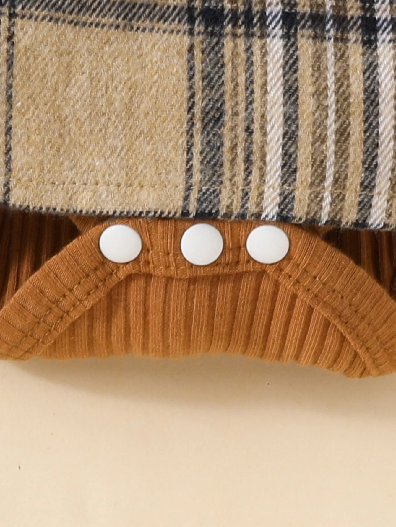 Close-up of Baby Girls Long Sleeve Plaid With Bow featuring snap buttons and ribbed brown fabric