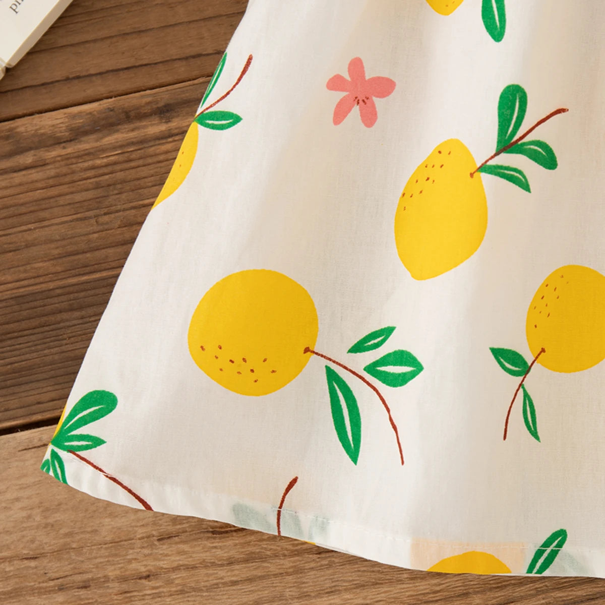Close-up of Beach Dress Casual Fruit Printed with Hat Suit featuring yellow fruit and green leaves on white fabric 