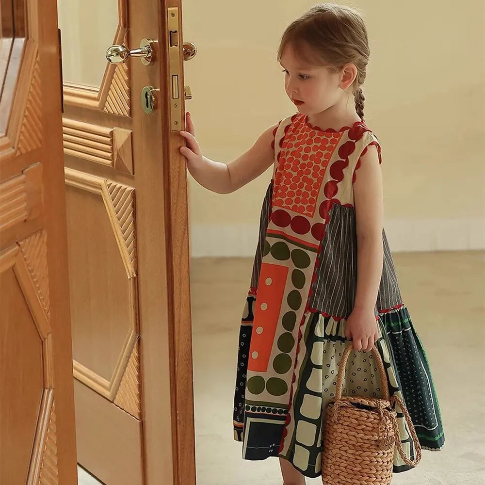 Girl wearing Bear Leader Girls Summer Dress Round Neck Sleeveless Multicolor Geometric Dress standing by a wooden door holding a woven basket bag