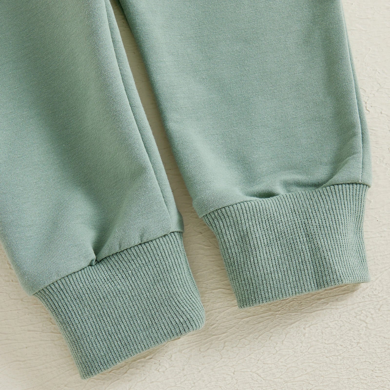 Close-up of green pants cuffs from BeQeuewll Toddler Fall Suit Animal Print Sweatshirt & Pants First Birthday Set