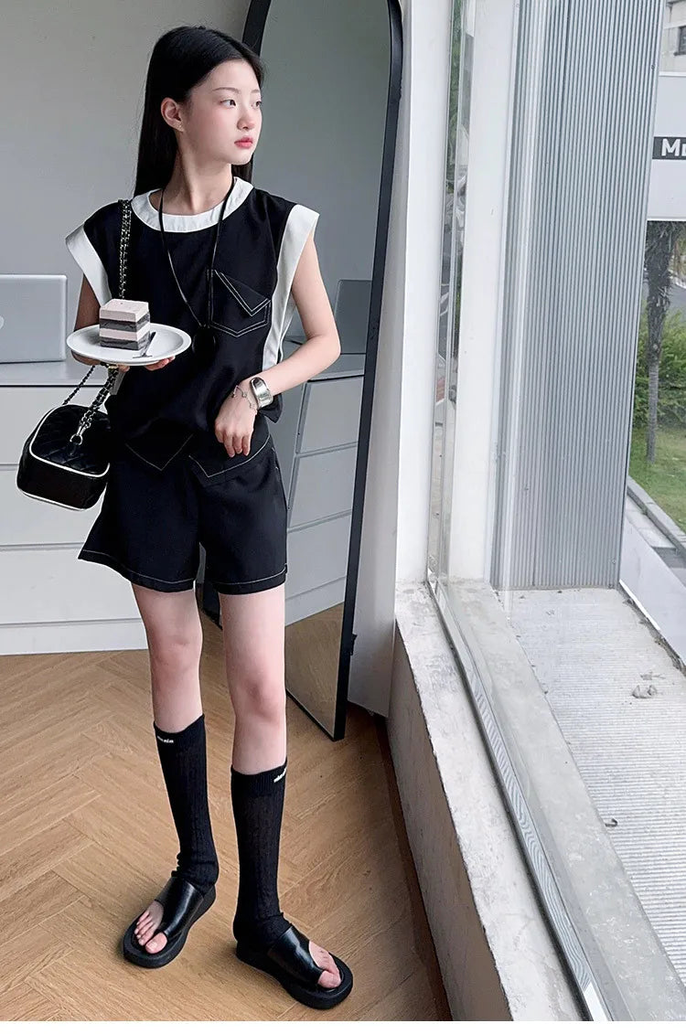 Woman wearing Black and White Spliced Vest and Shorts Two-Piece Casual Sports Outfit Set standing indoors near window