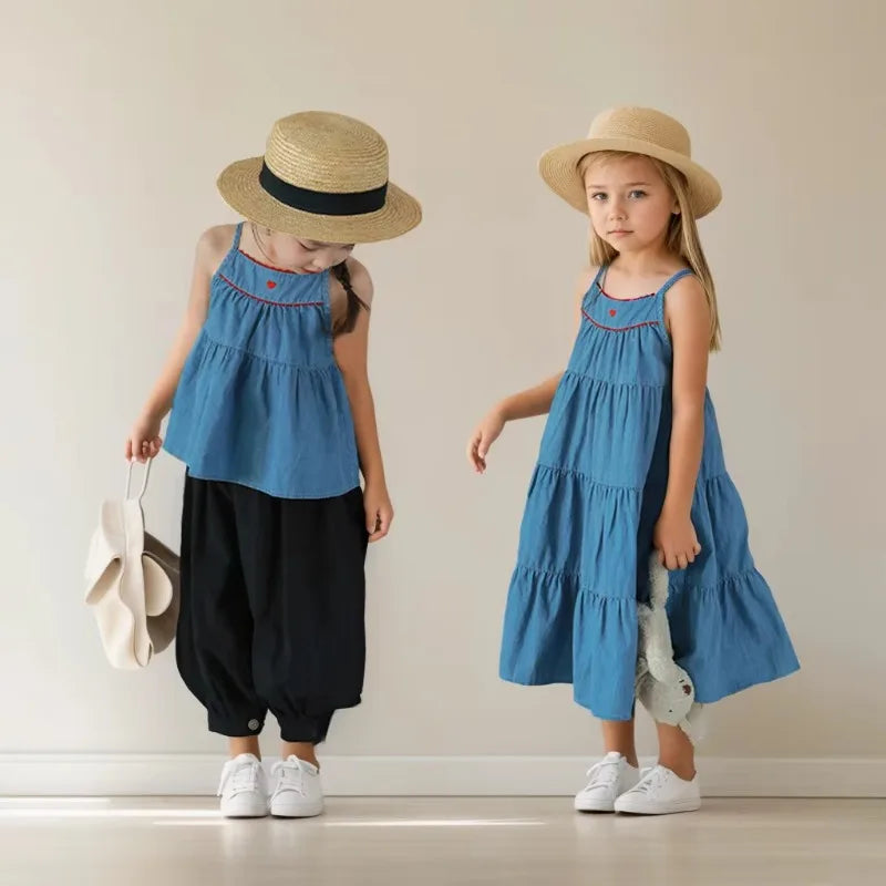 Two young girls wearing blue sleeveless casual dress beach party dress for kids and straw hats indoors