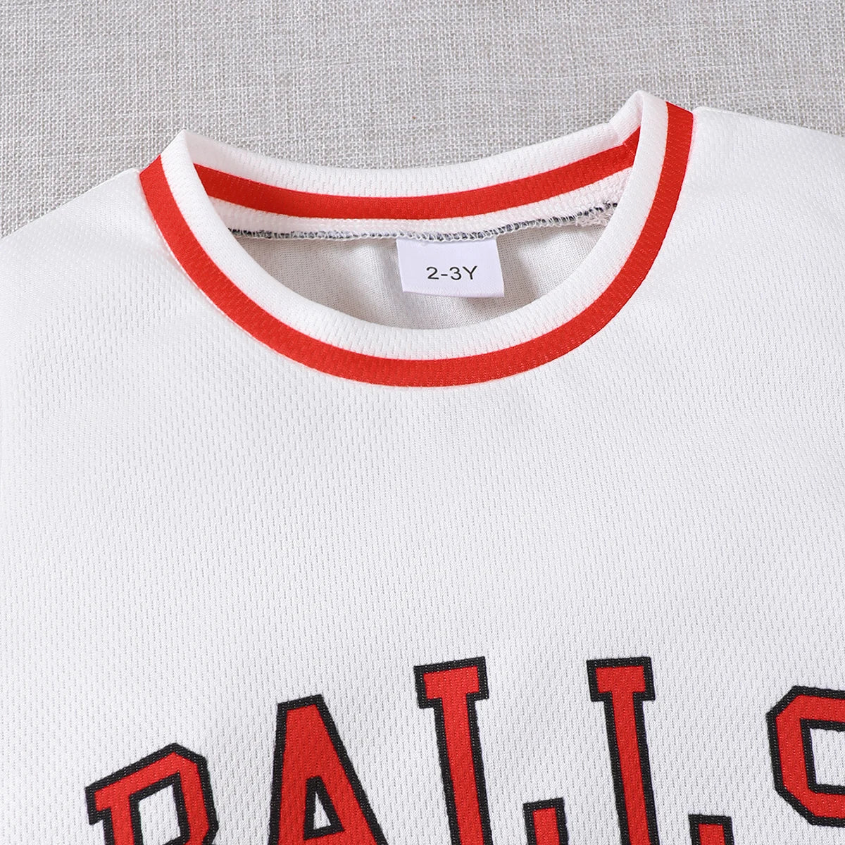 Close-up of white boys sports style set round neck letter 23 basketball suit 2 piece summer outfit top with red trim