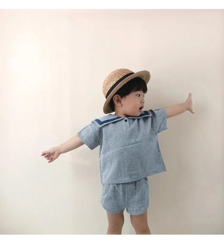 Toddler boy wearing Children Clothing Sets Boys Girls Muslin Top Shorts 2pcs Cotton Baby Outfit in light blue with a straw hat