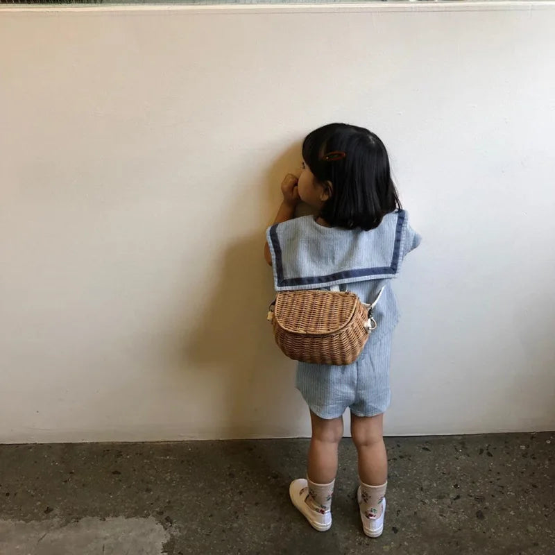 Toddler wearing Children Clothing Sets Boys Girls Muslin Top Shorts 2pcs Cotton Baby Outfit with a small wicker backpack