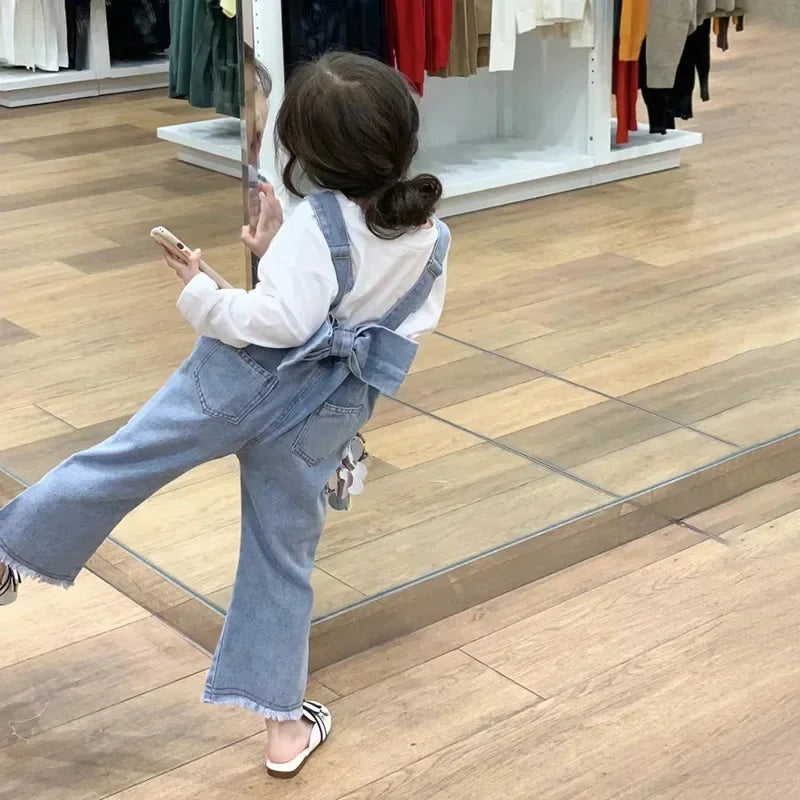 Children Clothing Sets Long Sleeve T Shirt Bow Suspenders Jeans Girls Baby Outfit worn by toddler girl playing in front of mirror