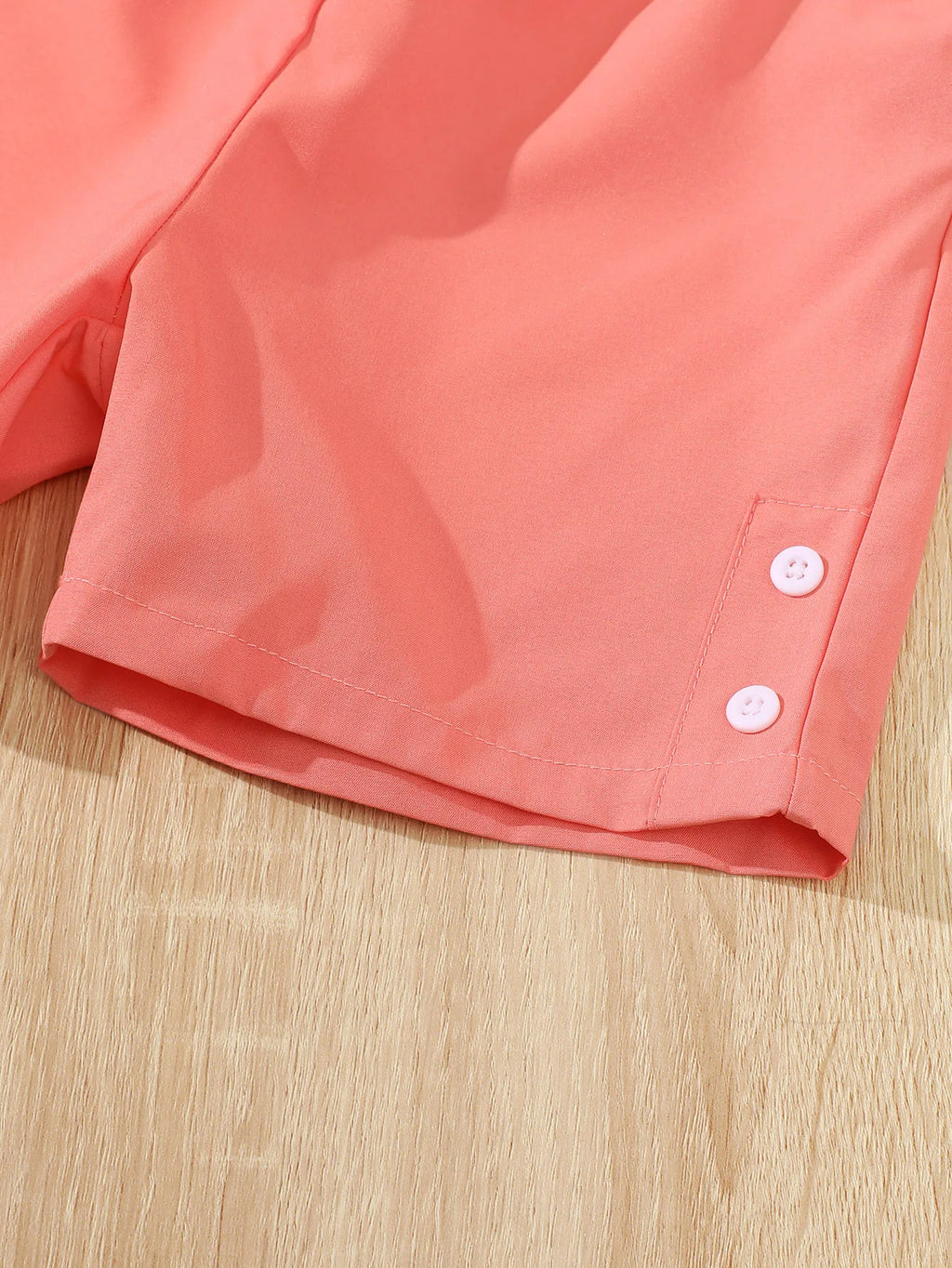 Close-up of coral shorts with button detail from Children Girls Summer Set Round Neck Floral Bow Sleeveless Top and Shorts 2Pc
