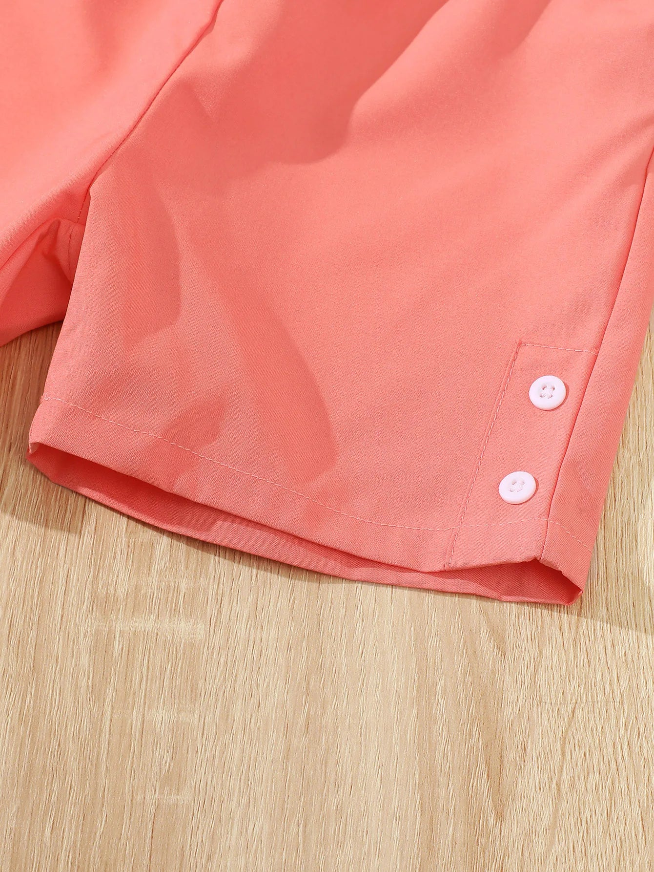 Close-up of coral shorts with button detail from Children Girls Summer Set Round Neck Floral Bow Sleeveless Top and Shorts 2Pc