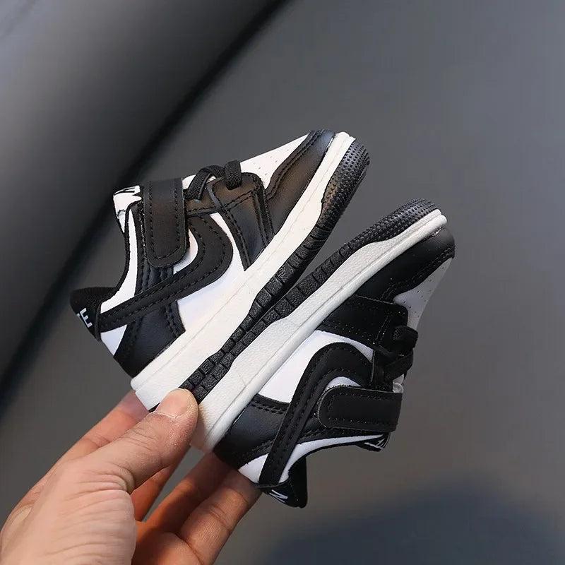 Children White Casual Sneakers Soft-Soled Running Shoes for Boys and Girls in black and white design held in hand