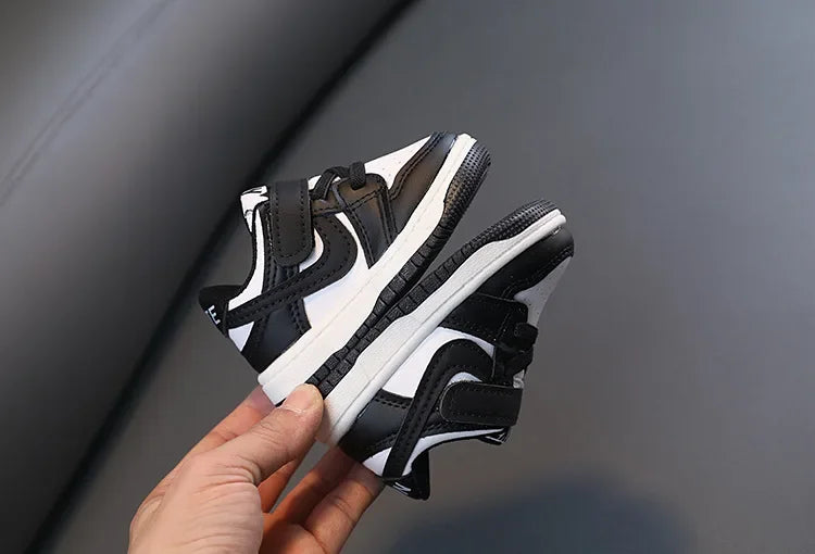 Children White Casual Sneakers Soft-Soled Running Shoes for Boys and Girls in black and white design held in hand 