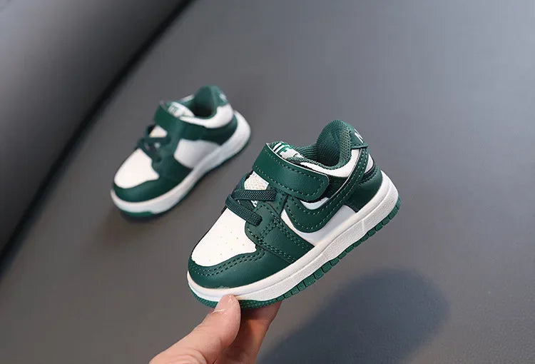 Children white casual sneakers soft-soled running shoes for boys and girls in green and white held in hand