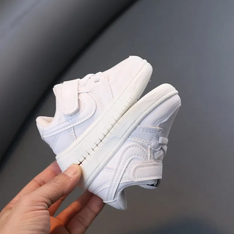 Children White Casual Sneakers Soft-Soled Running Shoes for Boys and Girls held in hand with velcro straps  