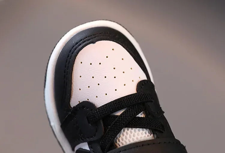 Black and white children's sneakers with breathable perforated design and secure laces