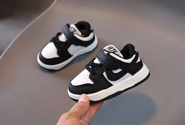 Black and white Nike children's sneakers with velcro strap and cushioned sole for comfort