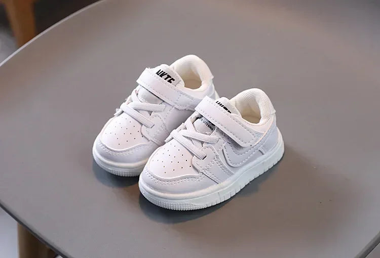 White children's sneakers with Velcro strap and laces by Yamza Tots' Closet on gray surface