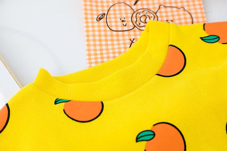 Close-up of cute baby clothes set casual t-shirt with bib denim overalls for kids with orange fruit print