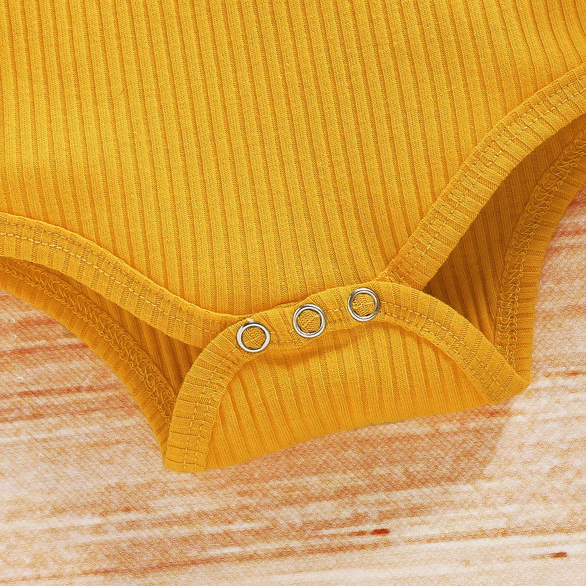 Close-up of Cute Baby Girl Clothing Set Yellow Romper Top and Sunflower Printed Shorts snap buttons