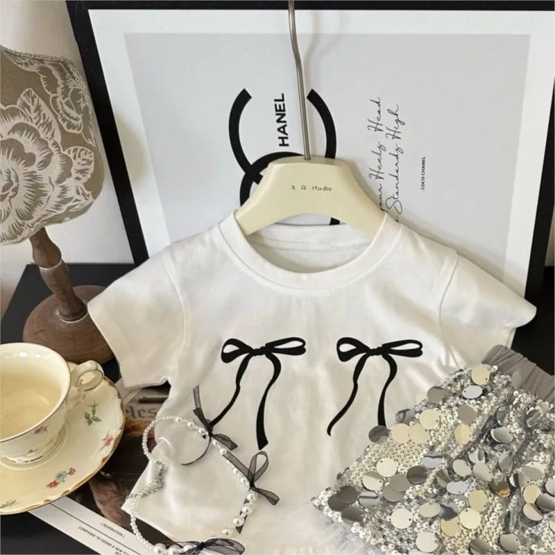 Fashion Baby Girl Bow T Shirt and Sequin Skirt Set Sparkle Kids Outfit displayed on hanger with decorative cups