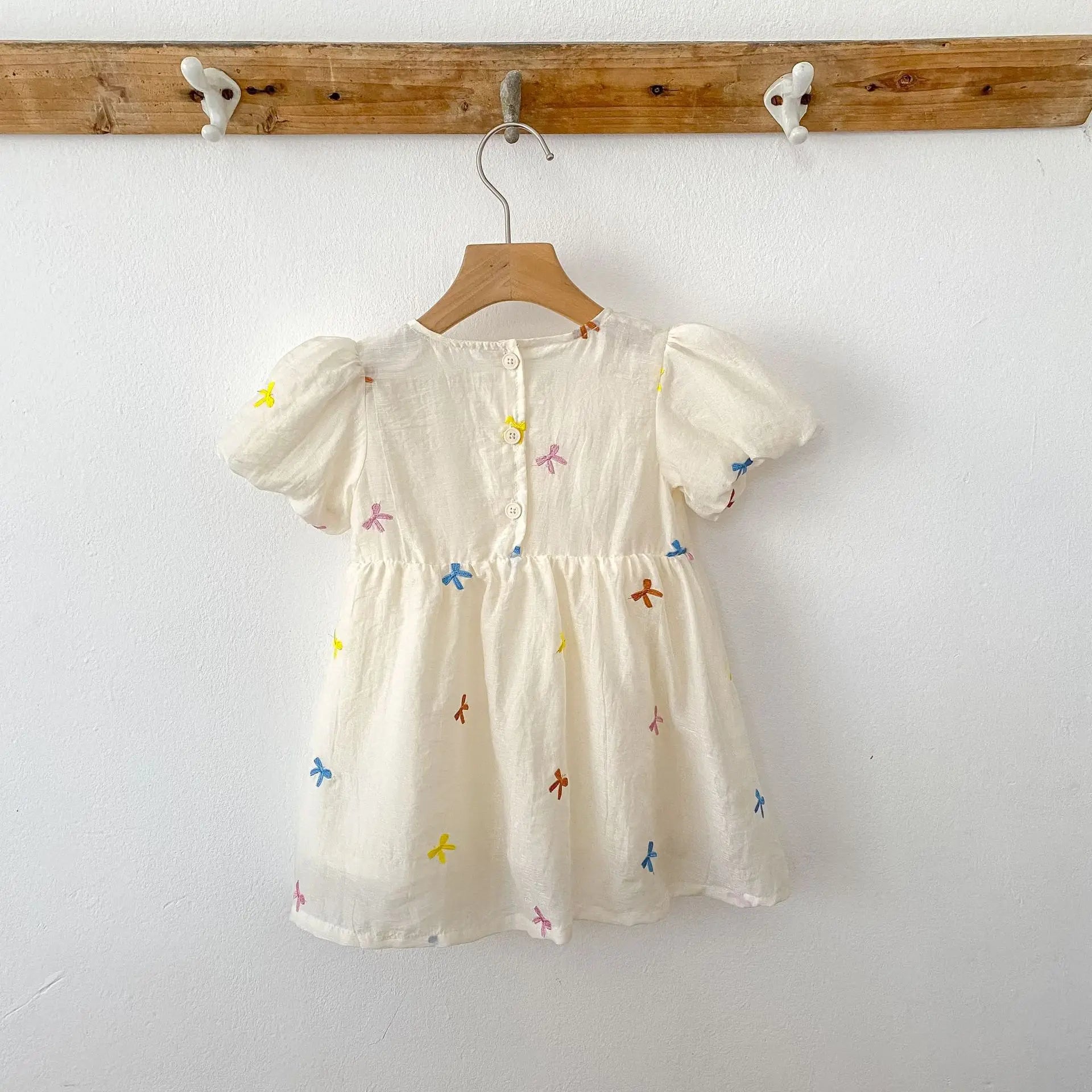 Fashion Baby Girls Embroidered Bow Puff Sleeve Cotton Backless Princess Dress hanging on wooden hanger