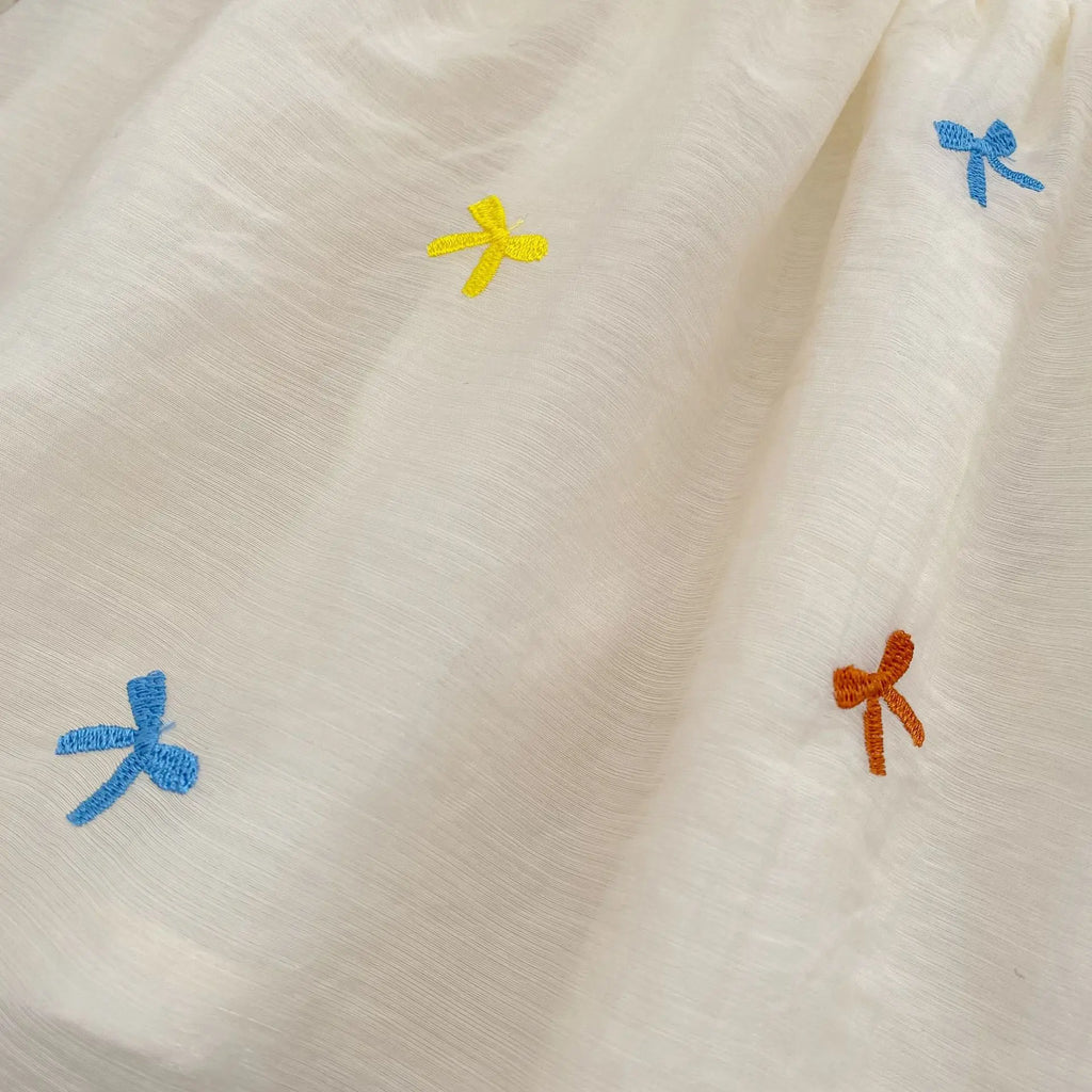 Close-up of Fashion Baby Girls Embroidered Bow Puff Sleeve Cotton Backless Princess Dress with colorful embroidered bows on white fabric