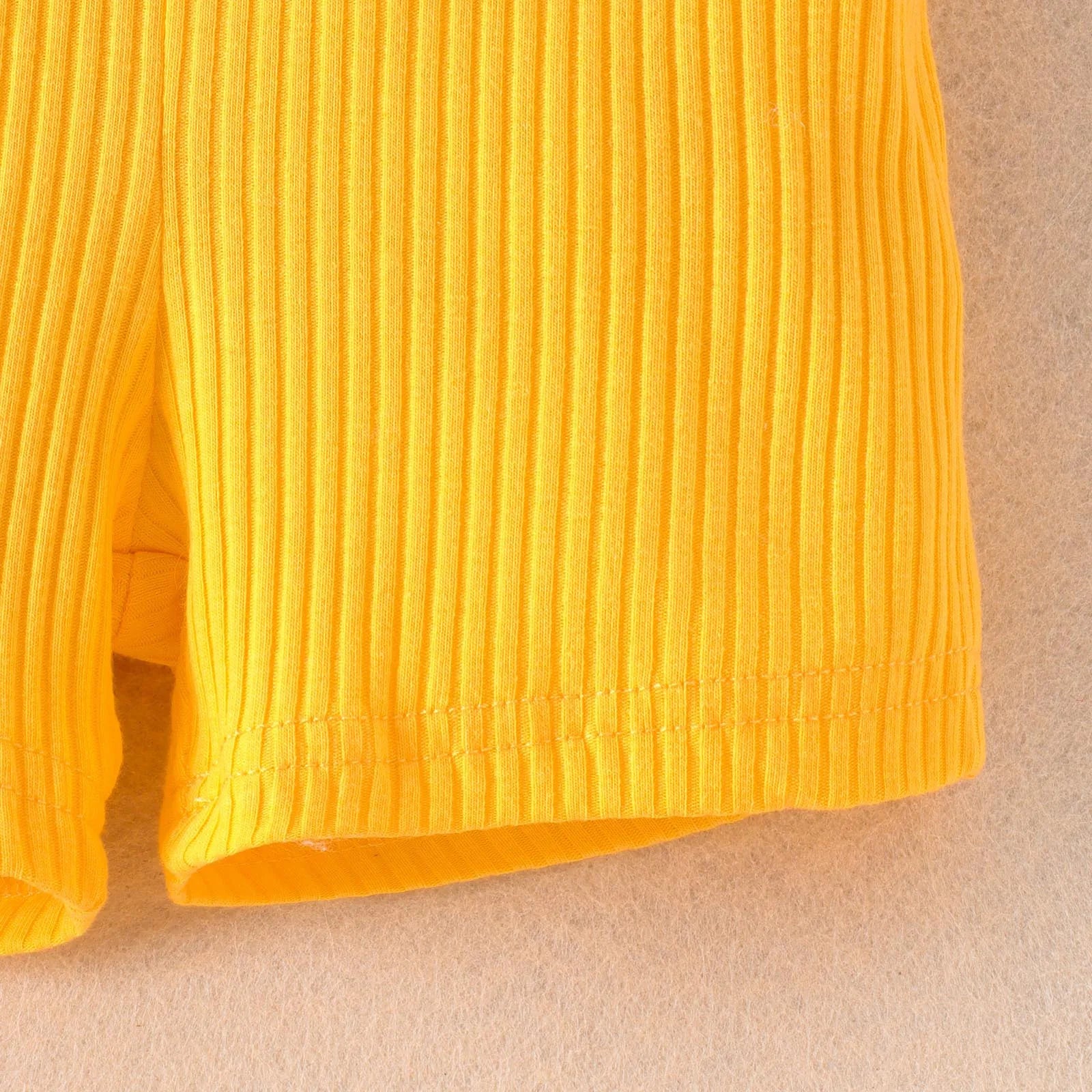 Close up of yellow girls summer sleeveless solid rib bodysuit fabric showing texture and stitching
