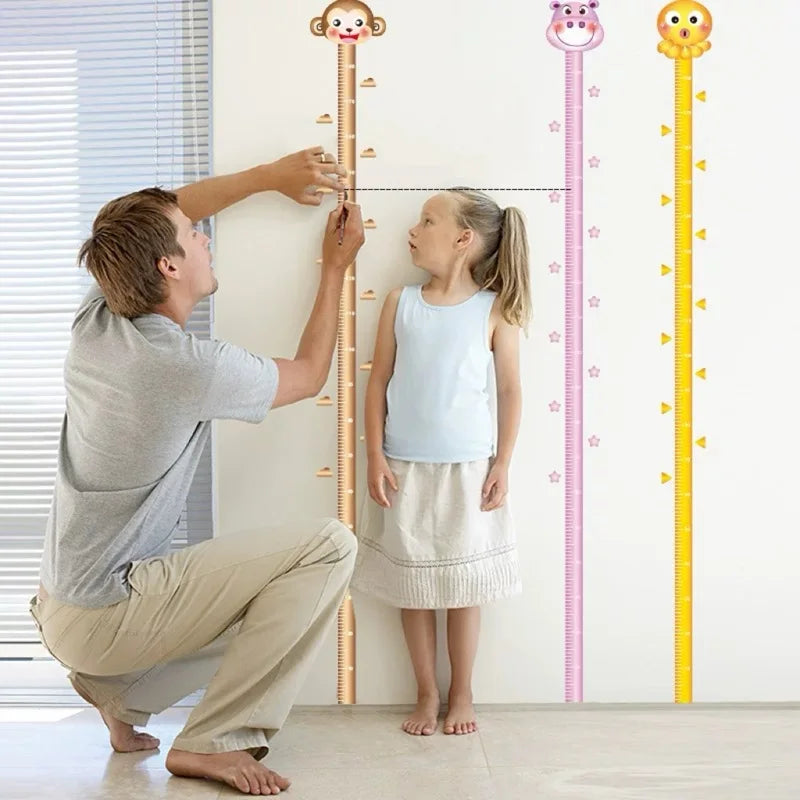 Dad measuring little girl height on wall ruler with animal designs in bright room