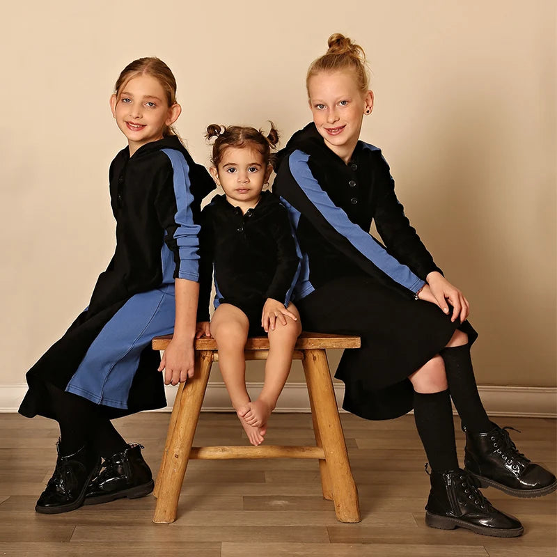 Kids Black Corduroy Hoodie Dress with Denim Side Panel and Kangaroo Pocket worn by two girls sitting beside a toddler