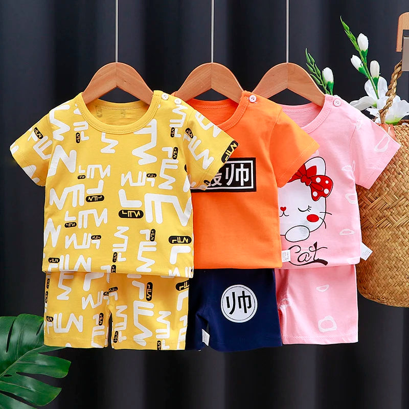 Kids Clothes Set Baby Boy & Girl Cotton T-Shirt & Shorts Summer Cartoon Outfit in yellow, orange, and pink hanging on wooden hangers