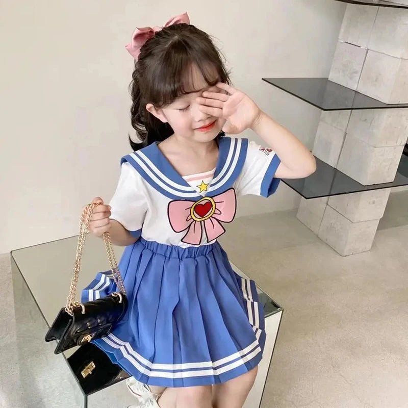 Kids Girls Cartoon Bow T-Shirt and Pleated Skirt Set Sailor Moon Cosplay Outfit worn by girl with pink hair bow holding black purse