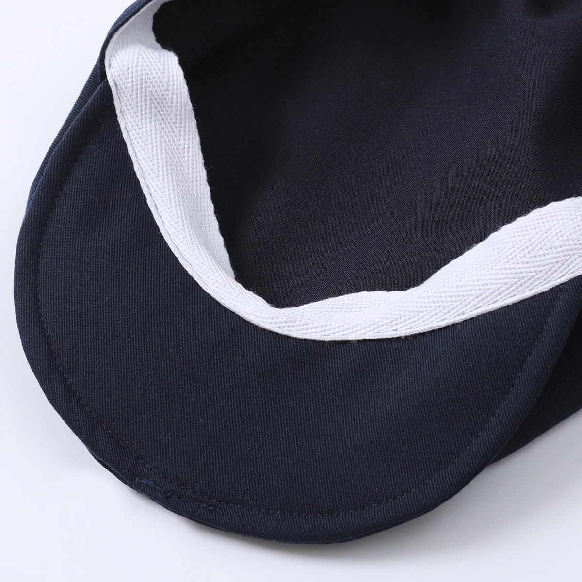 Close-up of a navy blue cap with a white trim, showcasing the inner lining and craftsmanship.