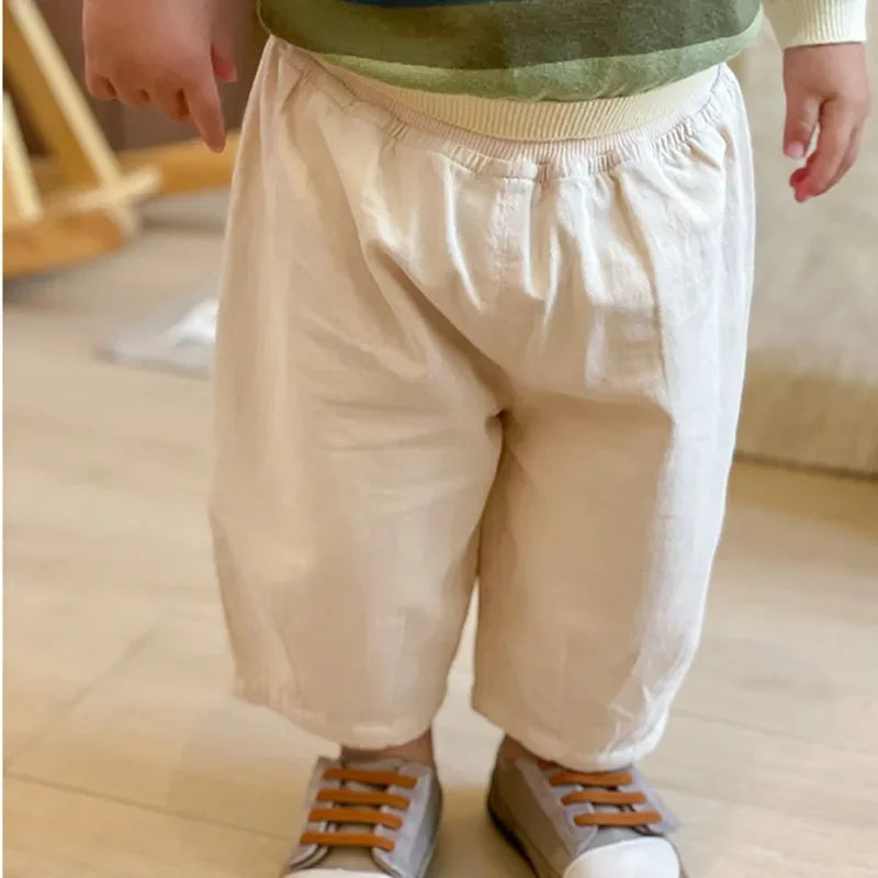 Solid Kids Fashion Trousers Casual Loose Pocket Ankle Length Pant for Boys Girls in beige worn by toddler with sneakers