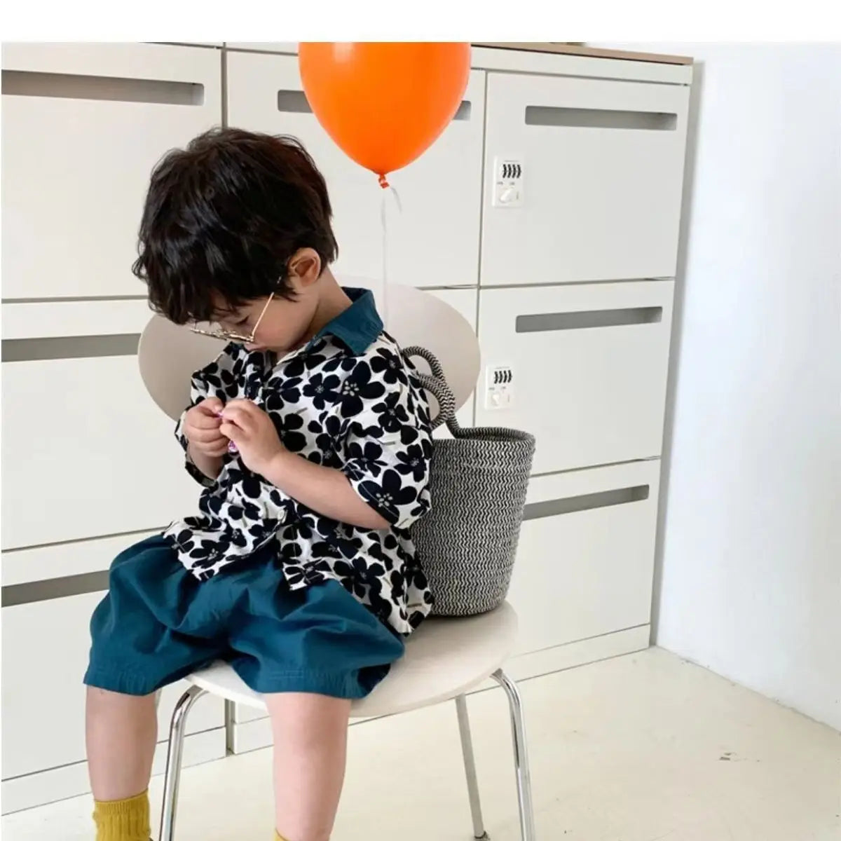 Child wearing Stylish Flower Suit for Children Baby Short Sleeve Shirt and Casual Shorts Set sitting on a chair indoors