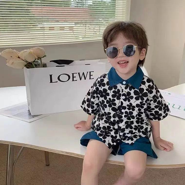 Child wearing Stylish Flower Suit for Children Baby Short Sleeve Shirt and Casual Shorts Set sitting on a table with sunglasses