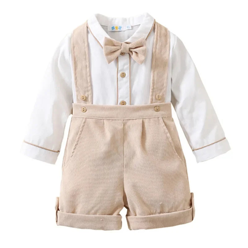 Toddler boys birthday outfit by Yamza Tots' Closet with beige suspenders shorts and white long sleeve shirt with bow tie