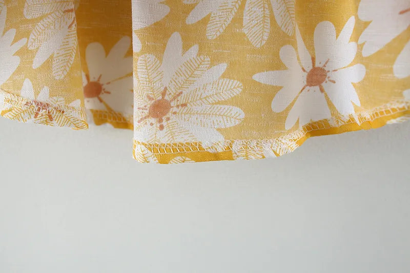 Close-up of yellow fabric with white daisy print from toddler girl clothes cotton beach collection by Yamza Tots Closet